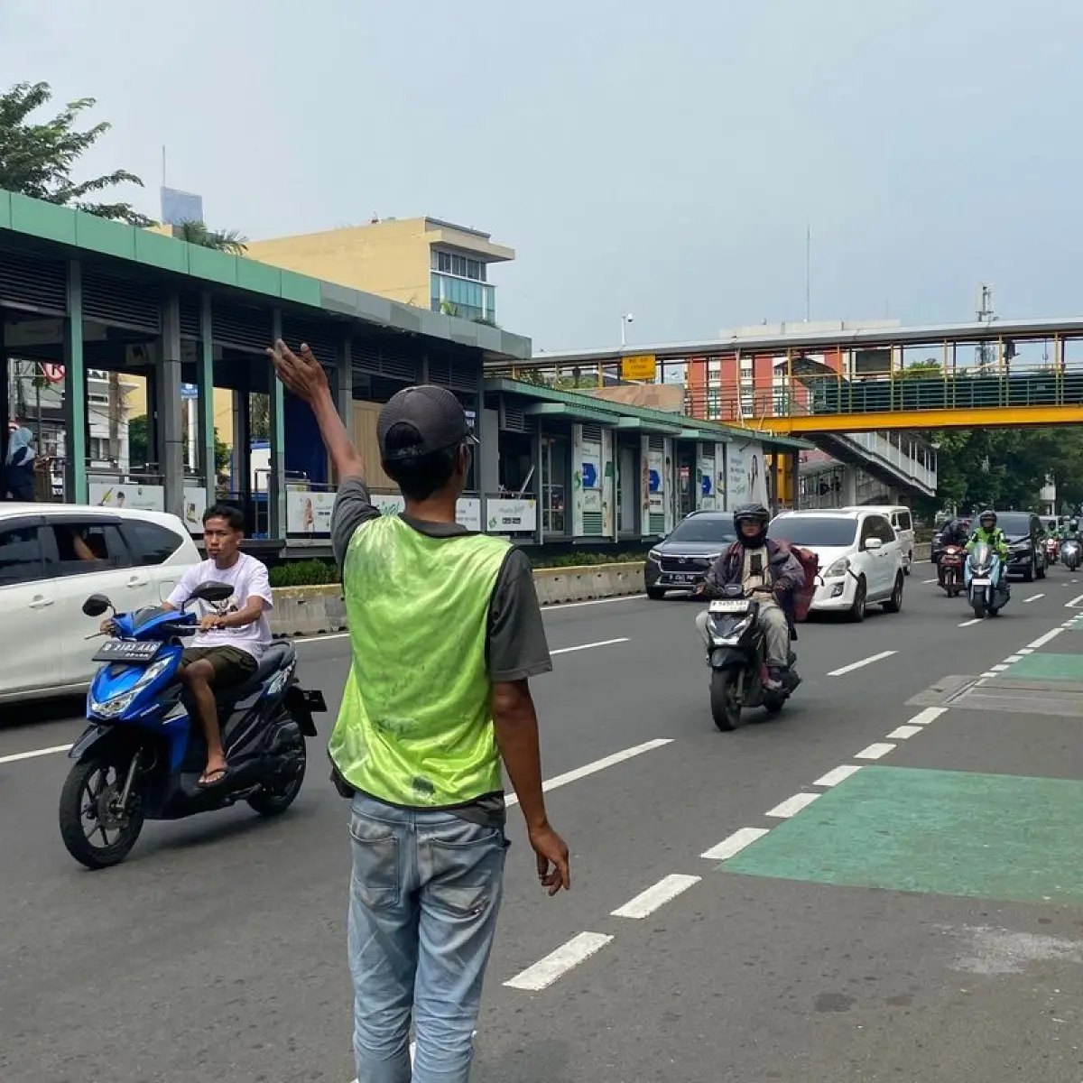 Pencari pelanggan jasa cat duco berdiri di bahu jalan kawasan Kramat Raya, Jakarta Pusat, untuk menawarkan jasa perbaikan baret dan penyok kendaraan kepada pengendara, Rabu (13/5/2026).(KOMPAS.com/LIDIA PRATAMA FEBRIAN )