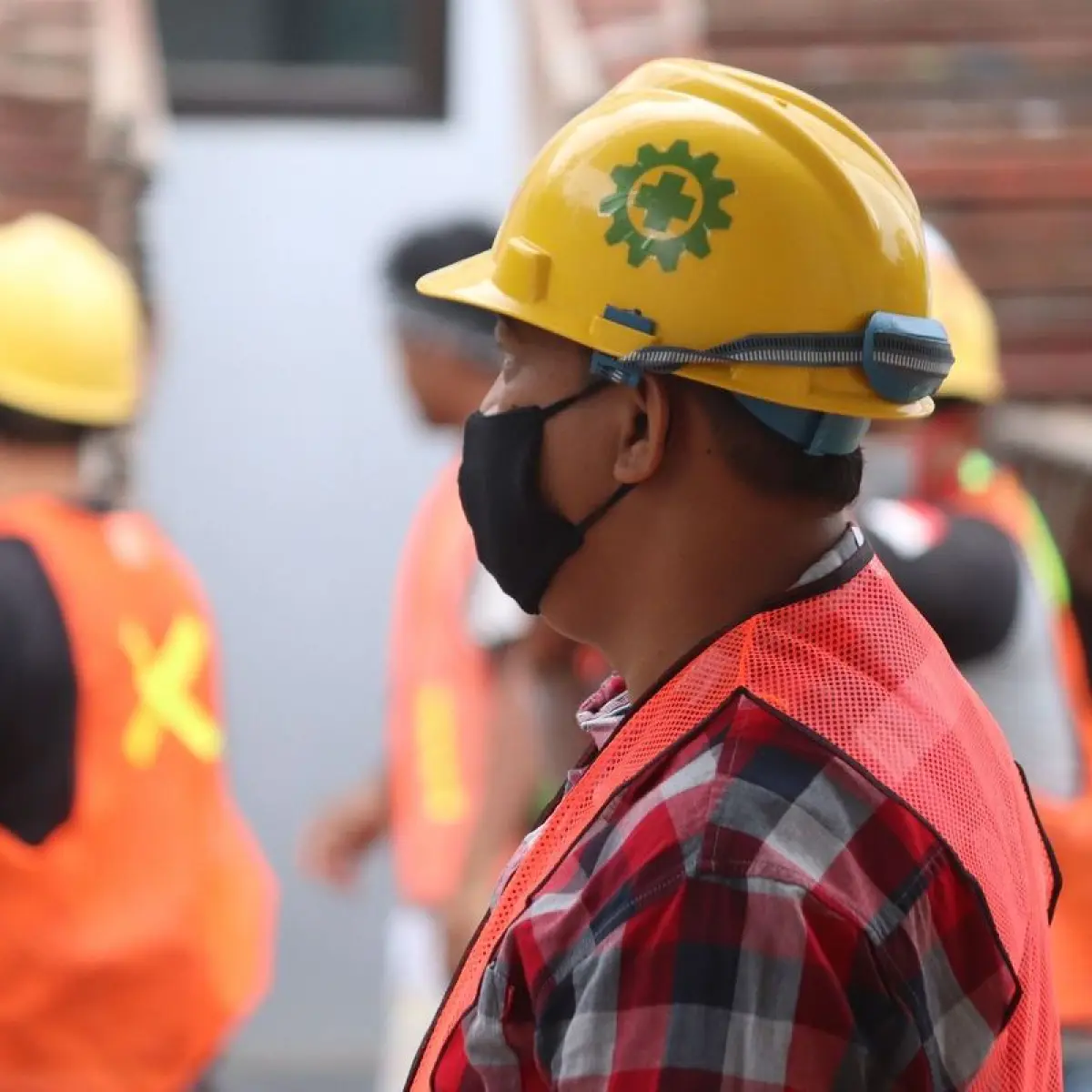 pekerja konstruksi memakai helm proyek mengamati maket bangunan modern (Foto: Aidsindonesia)