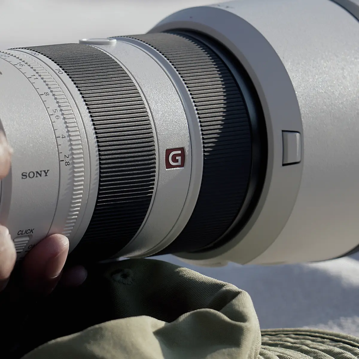 close-up lensa kamera super-telephoto hitam dengan ring fokus di tangan fotografer (Foto: Sony)