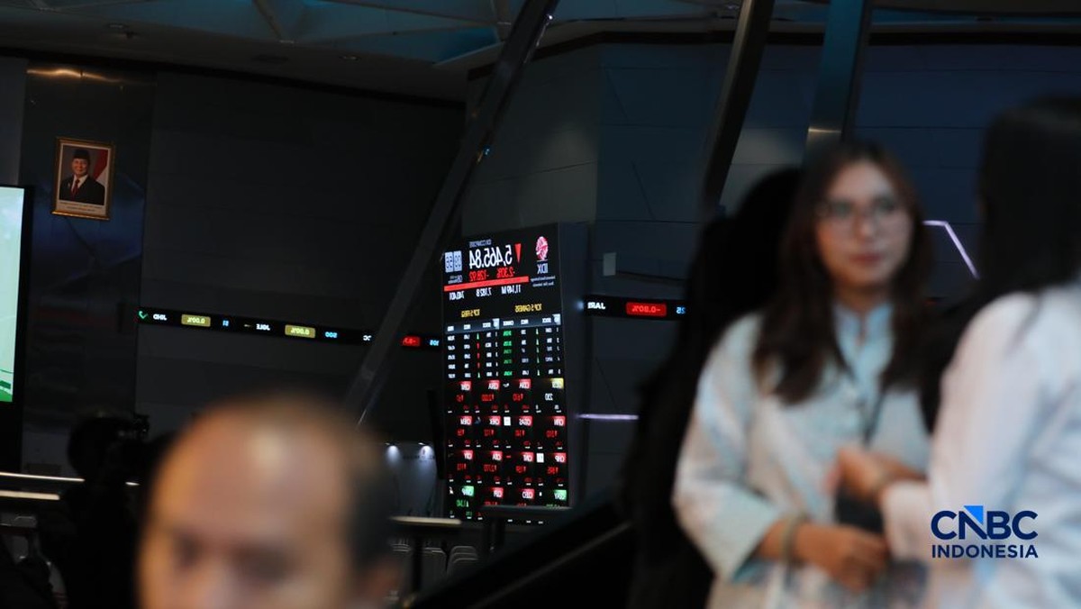 Pengunjung berfoto dengan latar belakang layar digital pergerakan Indeks Harga Saham Gabungan (IHSG) di Bursa Efek Indonesia, Jakarta, Senin (8/6/2026). (CNBC Indonesia/Tri Susilo)