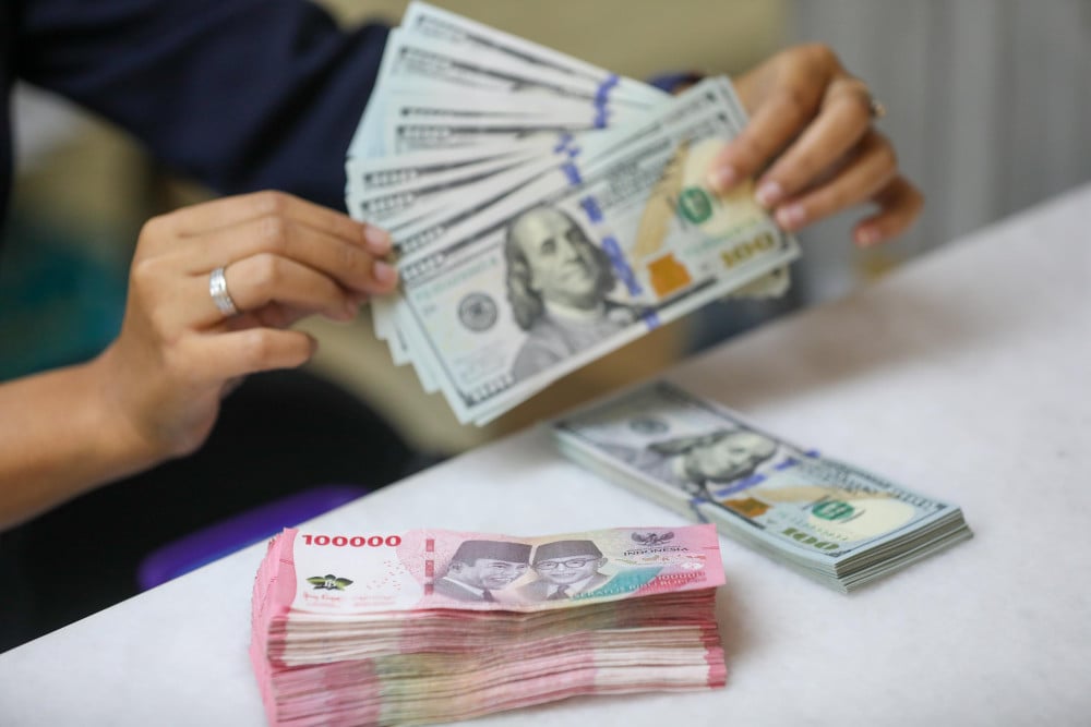 Pegawai menunjukan mata uang dolar Amerika Serikat (AS) dan rupiah di gerai penukaran uang atau money changer Ayu Masagung, Jakarta, Selasa (5/5/2026). Bisnis/Himawan L. Nugraha