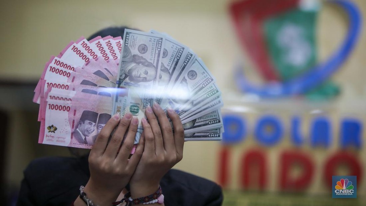 Foto: Petugas menjunjukkan uang pecahan dolar AS dan rupiah di Dolarindo Money Changer, Jakarta, Selasa (8/4/2025). (CNBC Indonesia/Faisal Rahman)