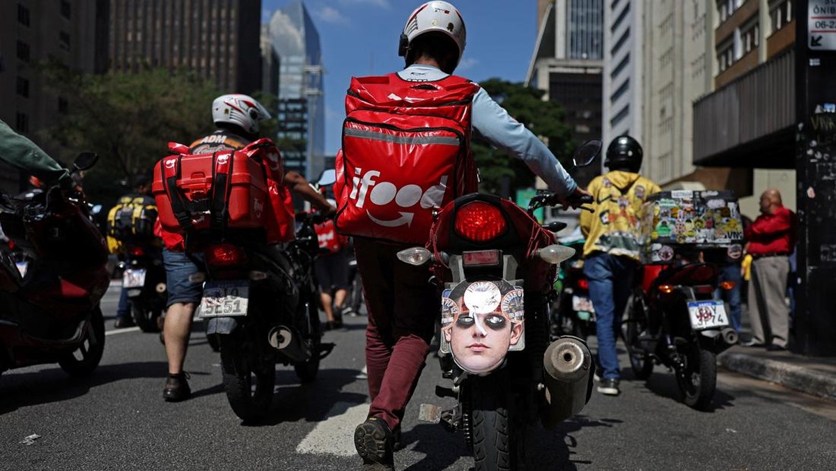 Foto: Seorang pria mendorong sepeda motornya dengan masker wajah bergambar Presiden Dewan Perwakilan Rakyat Brasil, Hugo Motta, terpasang selama protes para pekerja pengiriman barang untuk perbaikan kondisi kerja dan menentang rancangan undang-undang yang mengatur pekerjaan berbasis aplikasi, yang menurut mereka akan merusak keamanan kerja dan menguntungkan perusahaan teknologi, di Sao Paulo, Brasil, 14 April 2026. (REUTERS/Amanda Perobelli)