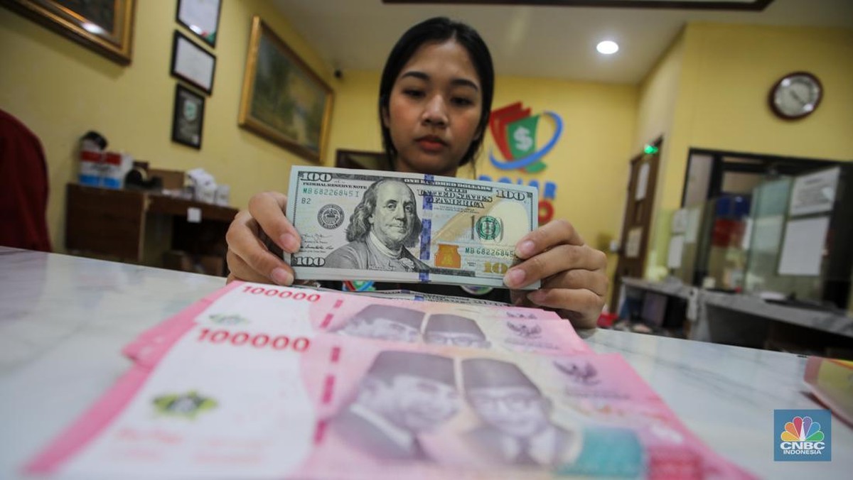 Foto: Petugas menjunjukkan uang pecahan dolar AS dan rupiah di Dolarindo Money Changer, Jakarta, Selasa (8/4/2025). (CNBC Indonesia/Faisal Rahman)