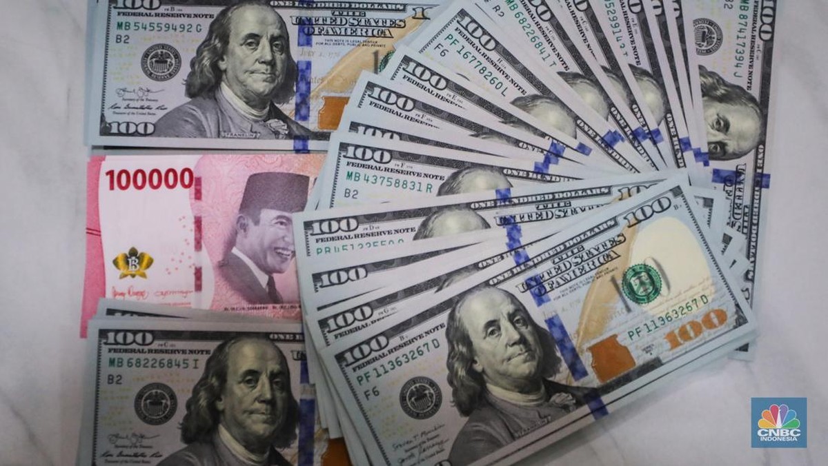 Foto: Petugas menjunjukkan uang pecahan dolar AS dan rupiah di Dolarindo Money Changer, Jakarta, Selasa (8/4/2025). (CNBC Indonesia/Faisal Rahman)