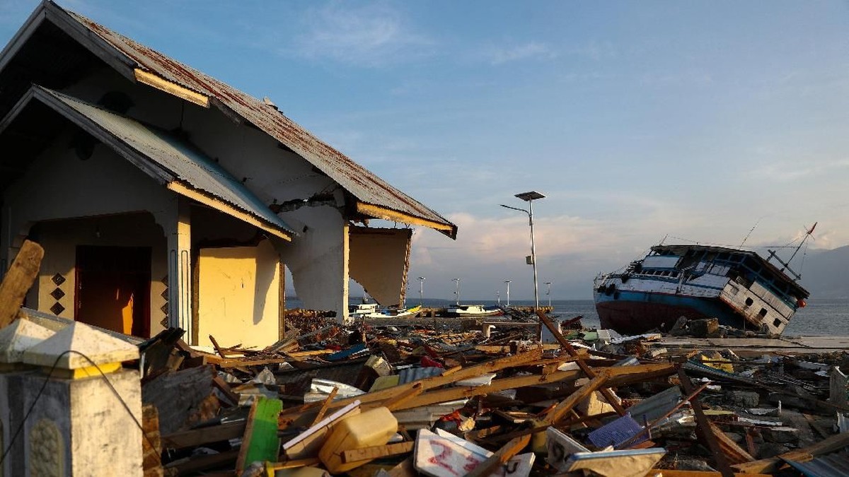 Foto: Pengendara sepeda motor naik melewati kapal yang rusak setelah gempa bumi dan tsunami menghantam sebuah area di Wani, Donggala, Sulawesi Tengah, Indonesia 3 Oktober 2018. REUTERS / Athit Perawongmetha
