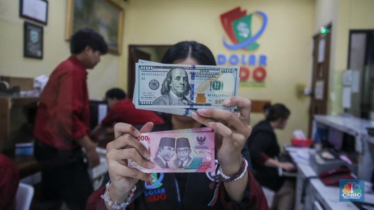 Foto: Petugas menjunjukkan uang pecahan dolar AS dan rupiah di Dolarindo Money Changer, Jakarta, Selasa (8/4/2025). (CNBC Indonesia/Faisal Rahman)