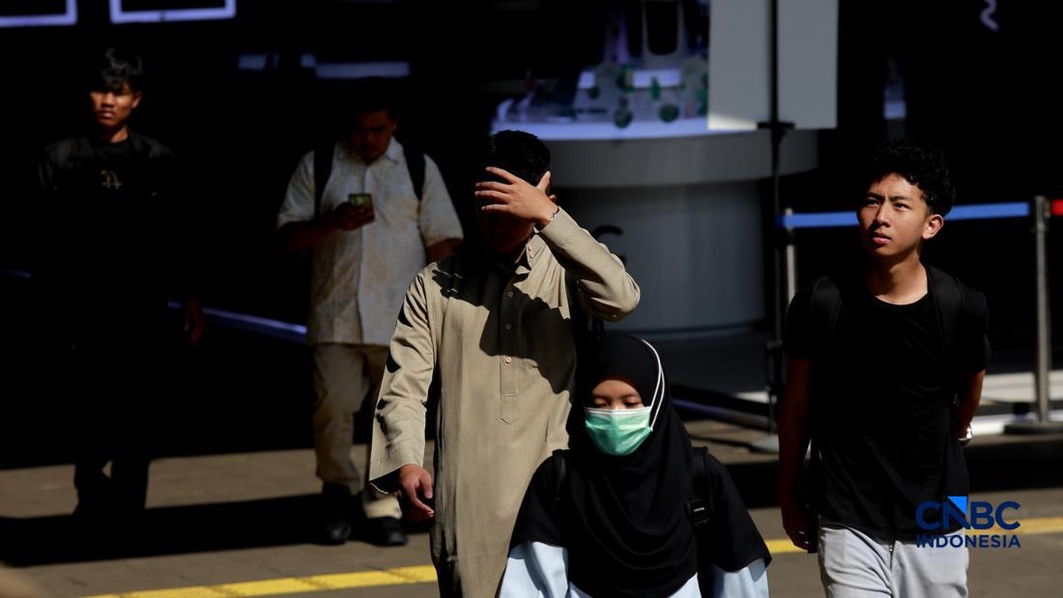 Foto: Warga berjalan dengan menutup kepala untuk berlindung dari terik matahari di kawasan Dukuh Atas, Jakarta, Selasa (17/3/2026). (CNBC Indonesia/Muhammad Sabki)
