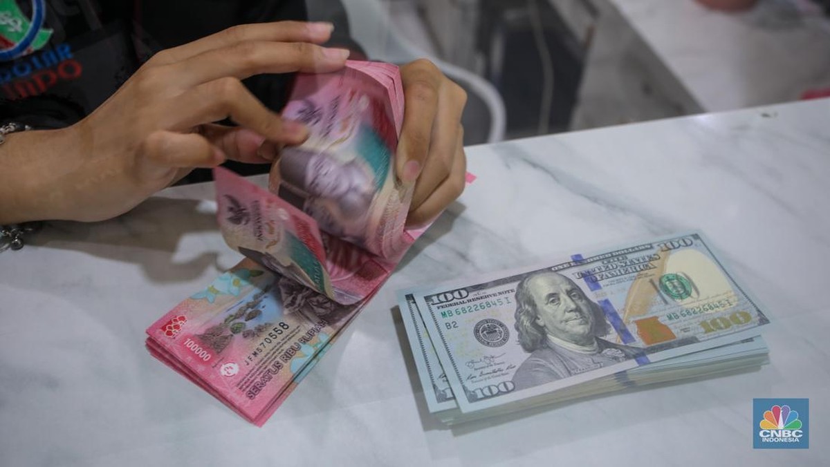 Foto: Petugas menjunjukkan uang pecahan dolar AS dan rupiah di Dolarindo Money Changer, Jakarta, Selasa (8/4/2025). (CNBC Indonesia/Faisal Rahman)