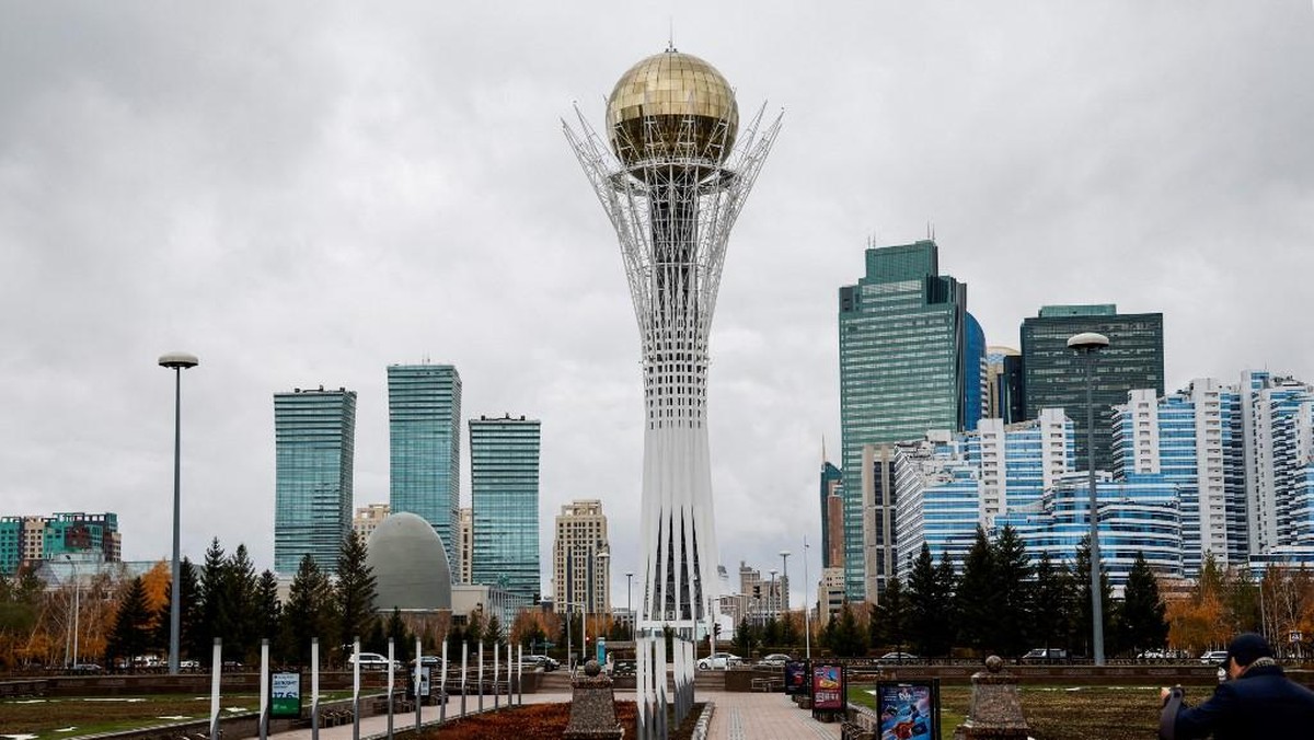 Foto: Pejalan kaki berjalan di dekat menara Baiterek (Bayterek) di bawah langit berawan, di Astana, pada 30 Oktober 2023. (AFP/LUDOVIC MARIN)