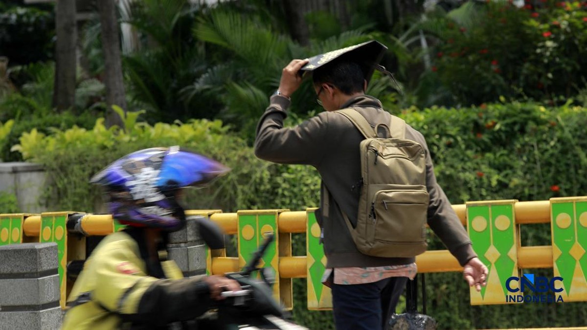 Foto: Warga berjalan dengan menutup kepala untuk berlindung dari terik matahari di Sudirman, Jakarta, Rabu (29/4/2026). (CNBC Indonesia/Muhammad Sabki)