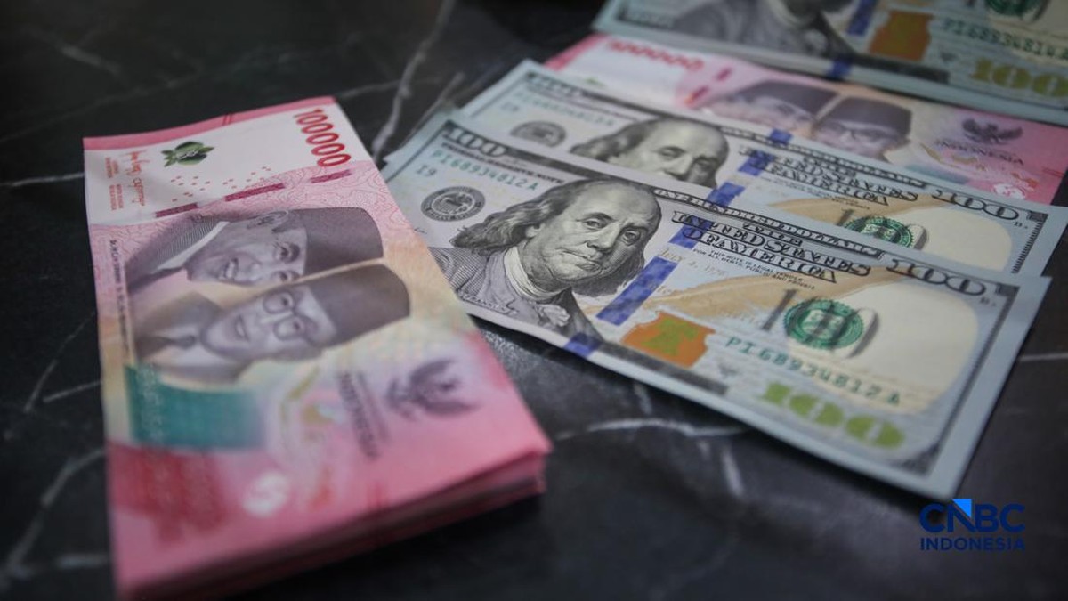 Foto: Petugas menjunjukkan uang pecahan dolar Amerika Serikat (AS) dan rupiah di Dolar Asia Money Changer, Jakarta, Rabu (8/7/2026). (CNBC Indonesia/Faisal Rahman)