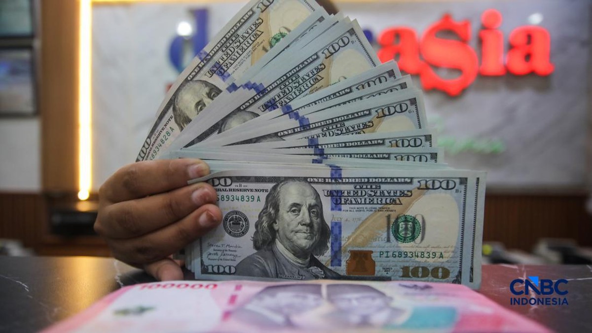 Foto: Petugas menjunjukkan uang pecahan dolar Amerika Serikat (AS) dan rupiah di Dolar Asia Money Changer, Jakarta, Rabu (8/7/2026). (CNBC Indonesia/Faisal Rahman)