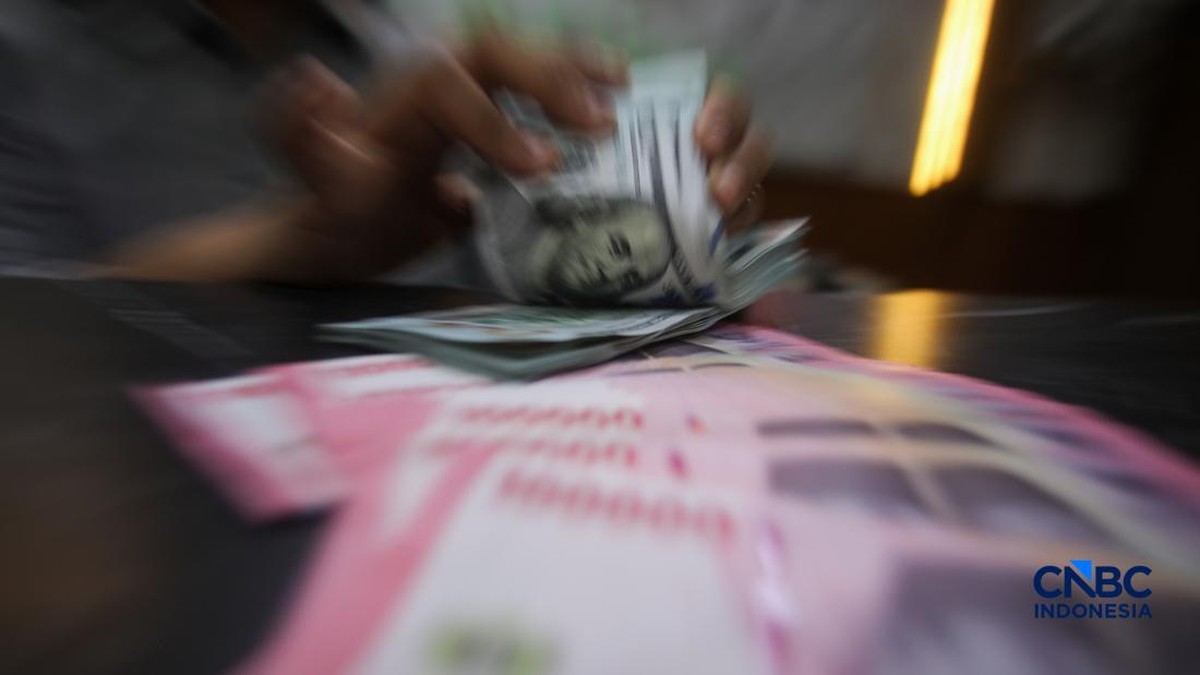 Foto: Petugas menjunjukkan uang pecahan dolar Amerika Serikat (AS) dan rupiah di Dolar Asia Money Changer, Jakarta, Rabu (8/7/2026). (CNBC Indonesia/Faisal Rahman)