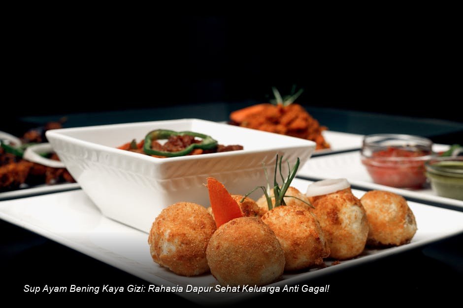 Semangkuk besar Sup Ayam Bening yang jernih dengan irisan wortel, kentang, dan taburan daun bawang segar terlihat mengepulkan uap hangat.